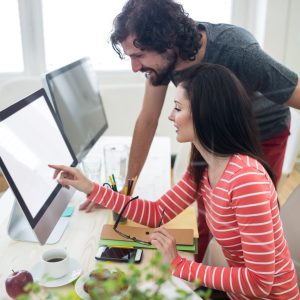 Male and female graphic designers interacting over computer in office